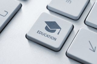 Close of of computer key labeled "education" with graduation cap and mortarboard.